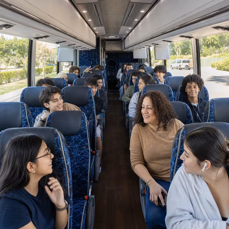 Group boarding a white charter bus for School Transportation transportation in Plano